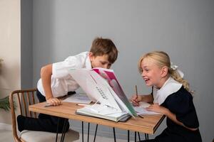 Children School Homework Classroom - Two children in school uniforms doing homework together at a desk in a classroom. photo