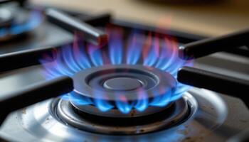 close up view of blue flames curling gently from a gas stove burner, casting faint shadows on the surrounding metal. photo