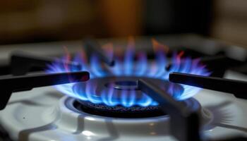 close up view of a thin blue gas flame flickering steadily from a stovetop burner in a dimly lit room. photo