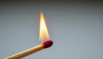 close up view of a slow burning matchstick with the flame engulfing the wood from the tip. photo