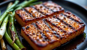 close up view of chargrilled tofu steaks basted in spicy hickory glaze, resting beside burnt scallions. photo