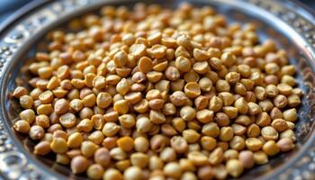 close up view of mustard seeds clustered on a vintage brass plate, showcasing varying shades of yellow and brown. photo