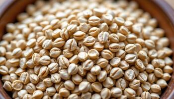 close up view of coriander seeds dried to a pale tan color, clustered in a wooden bowl with visible grain. photo