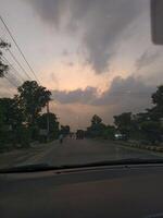 Driving on road at sunset with cloudy sky and trees landscape car view travel photography scenic highway photo