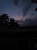 View of twilight sky from car window with clouds and trees silhouette for travel and nature photography photo