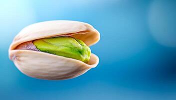 Pistachio nut in shell close-up. A pistachio nut partially opened, revealing its green inner kernel against a soft blue background. photo