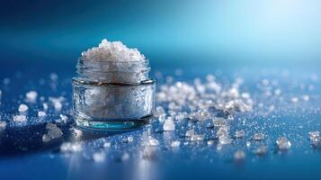 Bath salts in glass container displayed with scattered crystals on a blue surface during a relaxing ambiance photo