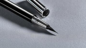 Black eyeliner pen with chrome details placed elegantly on a soft gray surface photo