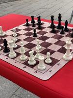 Chess board with pieces on outdoor table, red tablecloth, background for strategic concepts photo