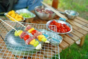 A person is cooking skewers of meat and vegetables on a grill photo