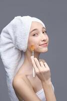 Girl with towel applying skincare product photo