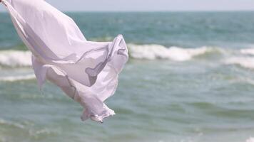 White cloth billows against a backdrop of ocean waves. video