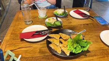 A table set with crispy shrimp pancakes and fresh greens in a well-lit Vietnamese restaurant, capturing a casual dining moment video