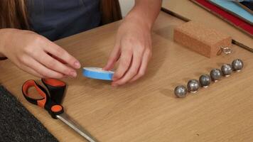 A person cuts tape and arranges metal spheres on a desk, demonstrating a simple experiment with precise hand movements video
