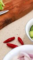 Chopping vegetables including cucumbers, shallots, and chillies on a wooden board in a well-lit kitchen video