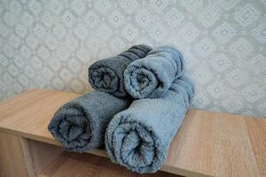 Four neatly rolled towels are skillfully arranged on a beautifully crafted wooden shelf, which adds a delightful charm and enhances the overall decor and aesthetics of the bathroom space photo