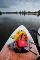 On the back of a paddle board, perched securely, there is a bright red first aid kit resting safely, always prepared for any potential emergencies while enjoying various water activities photo