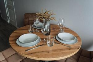 A beautifully crafted wooden table adorned with plates, utensils, and glasses set neatly on top, inviting everyone to gather around for a delightful meal and enjoyable conversation photo