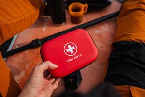 A person is firmly gripping a bright red first aid kit in their hands, fully prepared for any sort of emergency with all the essential medical supplies that are carefully stored inside photo