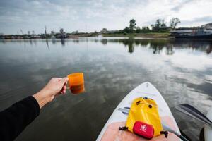 A person is comfortably sitting in a kayak, savoring a warm cup of coffee, while fully immersing themselves in the serene surroundings and the peaceful ambiance created by the gentle water photo