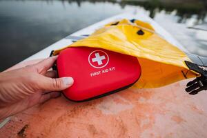 A person is firmly holding a comprehensive first aid kit in their hand, ready to provide assistance in case of an emergency or injury, ensuring safety and preparedness for any situation photo