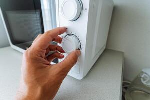 A person is in the process of adjusting the temperature settings of a microwave oven, ensuring that it functions perfectly for the food they plan to heat or cook inside it photo