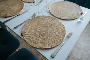A beautifully set dining table features elegant place mats, shiny silverware, sparkling glasses, and tasteful accessories, all arranged for a delightful dining experience photo