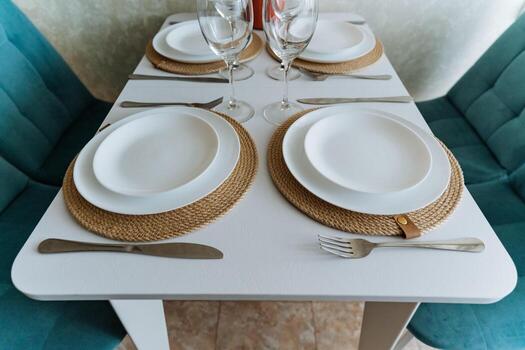 A beautifully arranged table is set with an array of plates, utensils, and elegant wine glasses placed strategically on it, creating an inviting dining atmosphere for guests photo