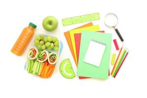 Brightly colored stationery and fresh snacks laid out on white surface, showcasing preparation for study session. Healthy options include fruits and vegetables. Isolated on white background photo