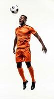 A man in an orange soccer uniform is jumping up to catch a soccer ball photo