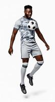 A man in a soccer uniform is jumping with a ball photo