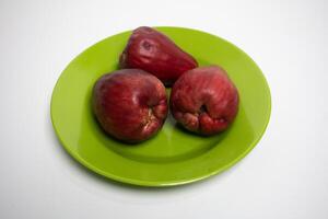 Three ripe water apples on a green plate, ready to eat. photo