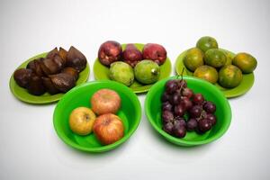 A colorful display of tropical fruits arranged neatly on green plates over a white background. photo