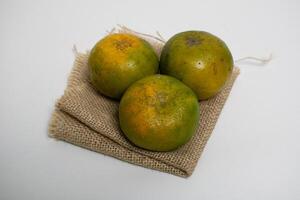 Three fresh oranges are placed on a folded burlap cloth, bringing a rustic and natural feel. photo