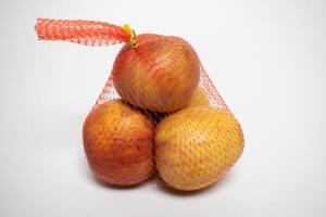 Three apples packaged in a red mesh bag. photo