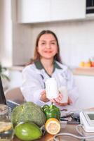 Dietitian in a white coat holds jars of dietary supplements and provides nutritional advice against the background of fresh vegetables and fruits. Curcumin, coenzyme q10. Health, wellness concept. photo