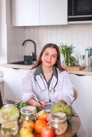 nutritionist in a white coat working at a table with fresh products and modern gadgets. nutrition concept, wellness programs. photo