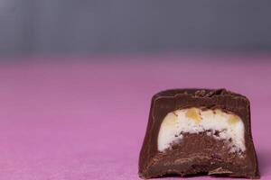 Chocolate candy with praline and pieces of walnut on a pink background close-up with space for copyspace text photo
