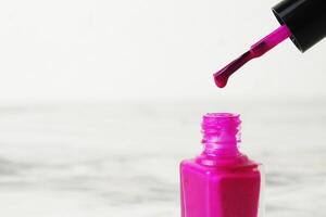 A drop of nail polish dripping from a brush close-up on a white background with space for copyspace text photo