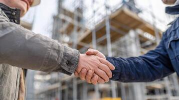Two construction workers shaking hands in front of a building photo