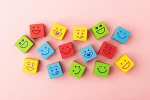 Group of Colourful Smiling Emoticon Diversity Face on Multi-colour Cube. Mind Mental Health. Happy Community. World Happiness, International Smiling Day. Table Top View photo