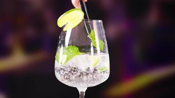 A mojito cocktail is prepared with lime and mint in a lively bar environment, highlighting vibrant colors and dynamic lighting video