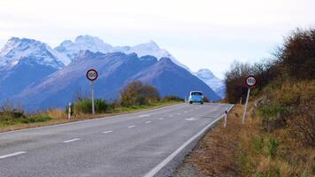 A car travels along a winding road with stunning mountain views in Glenorchy, New Zealand. Clear skies and natural beauty abound video