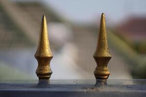 Two gold triangle-shaped objects with sharp ends and a blurred background photo