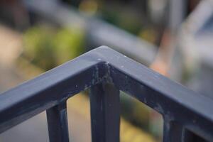 Corner of a black iron fence with blurred background photo