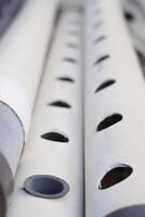 The white tube features round perforations distributed across its surface. photo