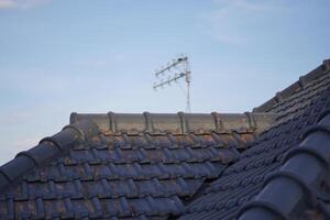A tv antenna placed on a tile with a blue sky photo