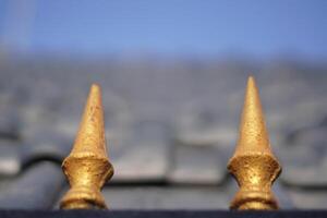 Two golden triangular shaped objects with sharp ends and a blurry blue sky background photo