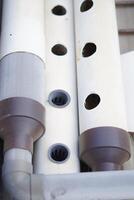 A white pipe runs with circular holes spaced evenly along its length. photo