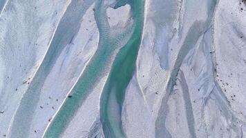 Aerial footage captures the intricate patterns of a turquoise braided river flowing through a rocky landscape in Glenorchy, New Zealand video
